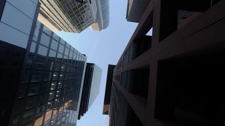 Frankfurt Downtown with Modern Skyscrapers and Glass Office Buildings seen through Green Trees. Business District with Corporate Skyline and Futuristic Cityscape. 4K Wide low angle shot