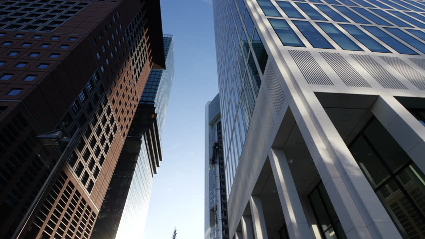 Frankfurt Downtown with Modern Skyscrapers and Glass Office Buildings seen through Green Trees. Business District with Corporate Skyline and Futuristic Cityscape. 4K Wide low angle shot