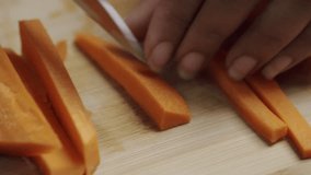 Handheld shot of Preparing Fresh Carrot Sticks for Cooking by Slicing Them on a Wooden Board - Powered by Shutterstock - Get 15% off with code: PIKWIZARD15
