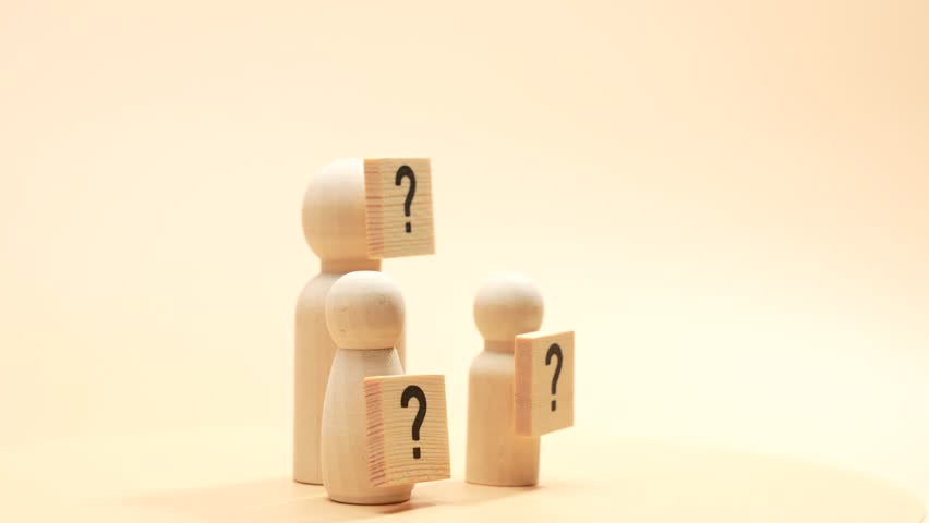 Three rotating wooden figures with a question mark. The concept of curiosity and uncertainty.