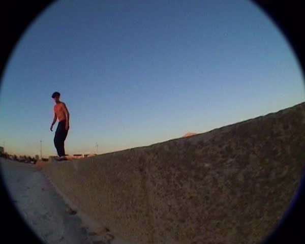 Vintage fisheye camcorder shot,a skateboarder does tricks on the beach at sunset Marseille, France