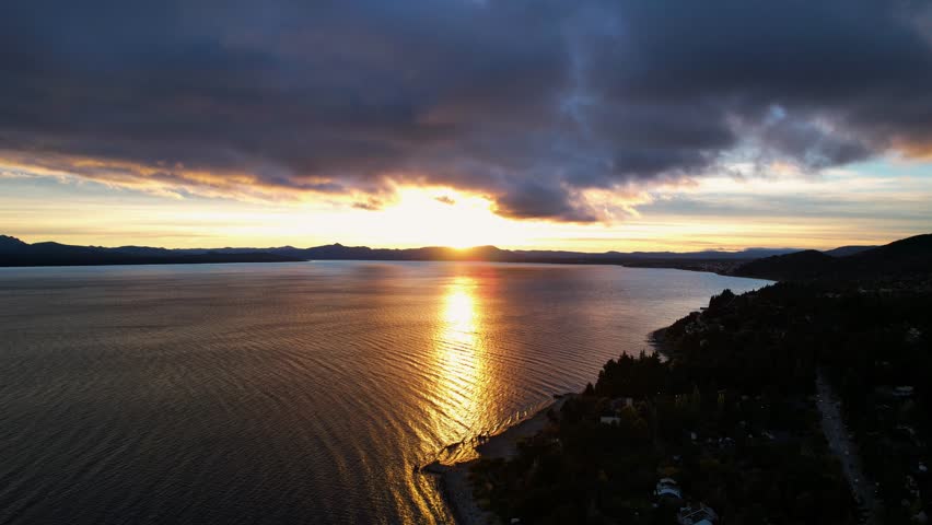 Aerial Drone Footage Captures A Stunning Sunrise Over Nahuel Huapi Lake, Argentina. The Sun Rises Above Mountains, Illuminating The City Below On A Bright Summer Morning.
