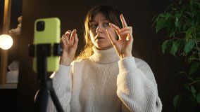 Content creator gesturing numbers seven and nine with her hands while recording a video on her smartphone. She is sitting in front of a black background - Powered by Shutterstock - Get 15% off with code: PIKWIZARD15