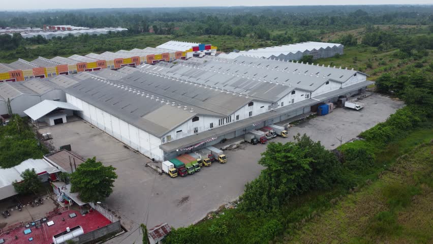 Aerial view of a goods distribution warehouse lined up with goods trucks parked in front of the warehouse