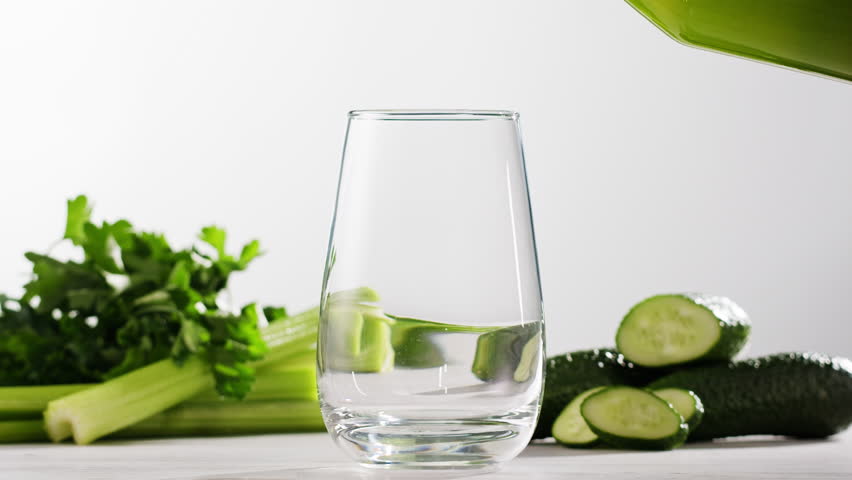 Fresh Green detox juice with cucumber, celery, apple and ginger and mint in glasses and jars. Pouring Vegan juice detox concept.