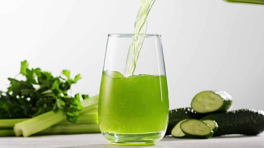 Fresh Green detox juice with cucumber, celery, apple and ginger and mint in glasses and jars. Pouring Vegan juice detox concept.