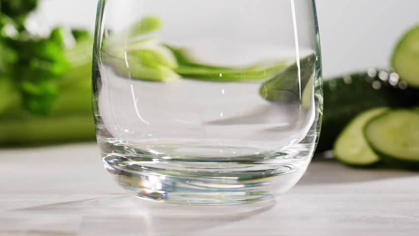Fresh Green detox juice with cucumber, celery, apple and ginger and mint in glasses and jars. Pouring Vegan juice detox concept.