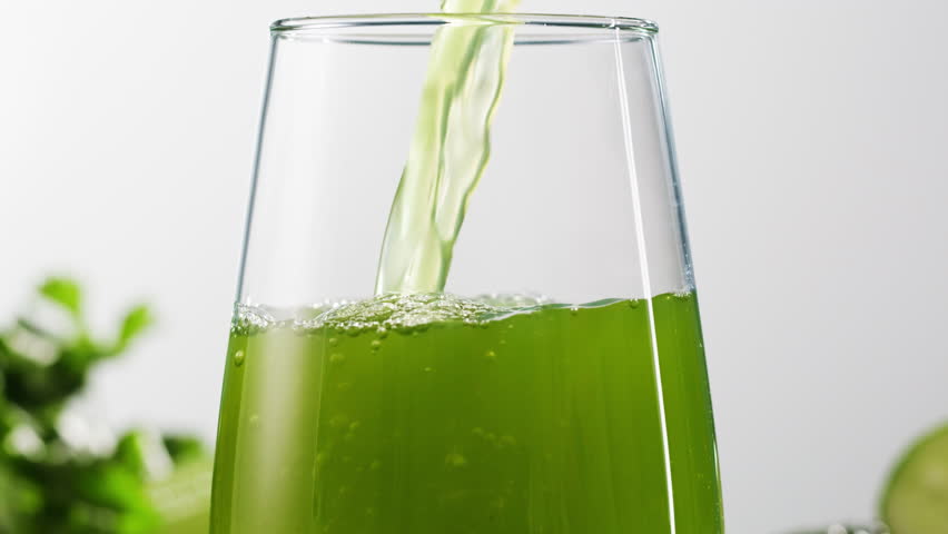 Fresh Green detox juice with cucumber, celery, apple and ginger and mint in glasses and jars. Pouring Vegan juice detox concept.