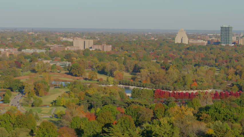 Aerial of Forest Park in St. Louis, Missouri on a pretty day in Autumn with a slow push over colorful trees towards the Grand Basin.