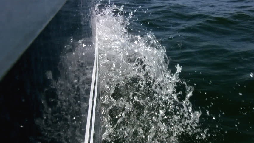 Wave breaks on the stem and the yacht is reflected in a smooth board the yacht.
