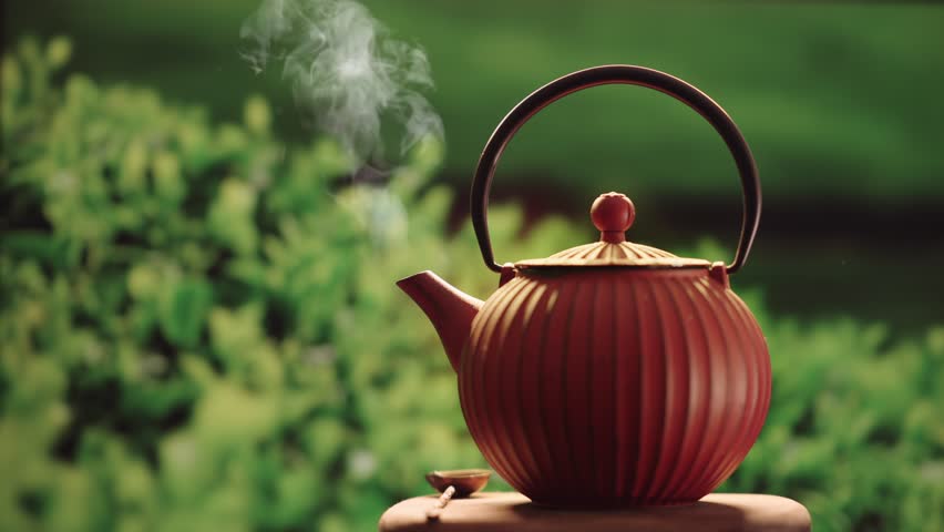 Steaming Teapot on wooden surface. Tea garden background outdoor