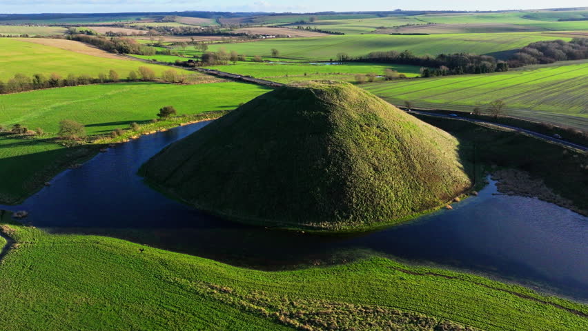 High aerial shot of Silbury hill with low winter sun and long shadows