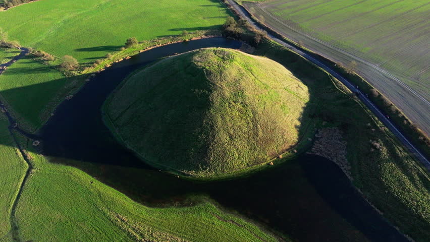 High aerial shot of Silbury hill with low winter sun and long shadows