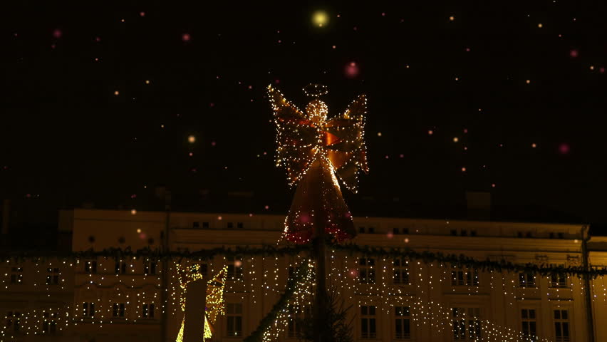 Christmas lights angel decoration in the shape of an angel holding a torch in from of Krakow, Poland. Unfocused street. Concept of winter holidays