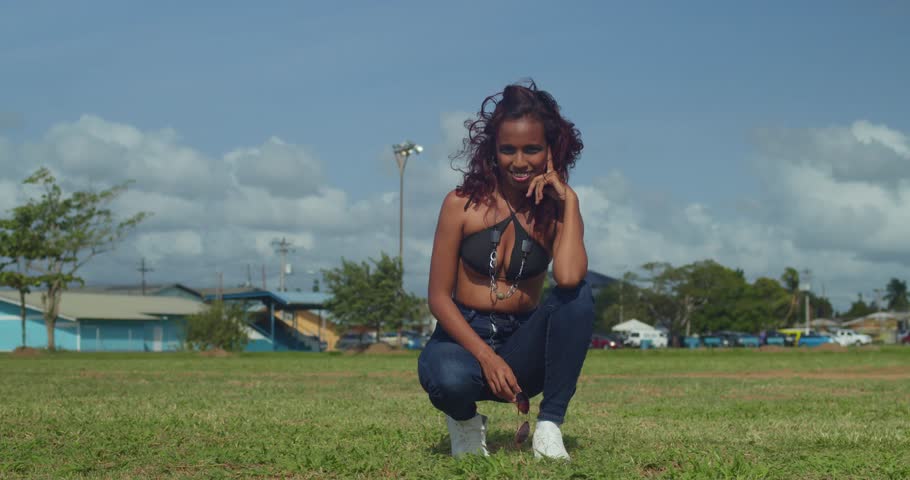 A girl with a bikini top and jeans takes in the beauty of a tropical park.