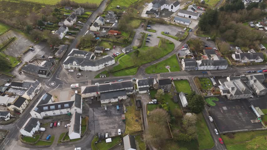 High-angle aerial view of Princetown, showcasing closely packed houses, slate rooftops, and local roads set amid green countryside and moorland terrain