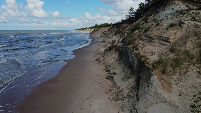 Drone flies over Baltic Sea cliffs at Jurkalne, showcasing dramatic coastal erosion