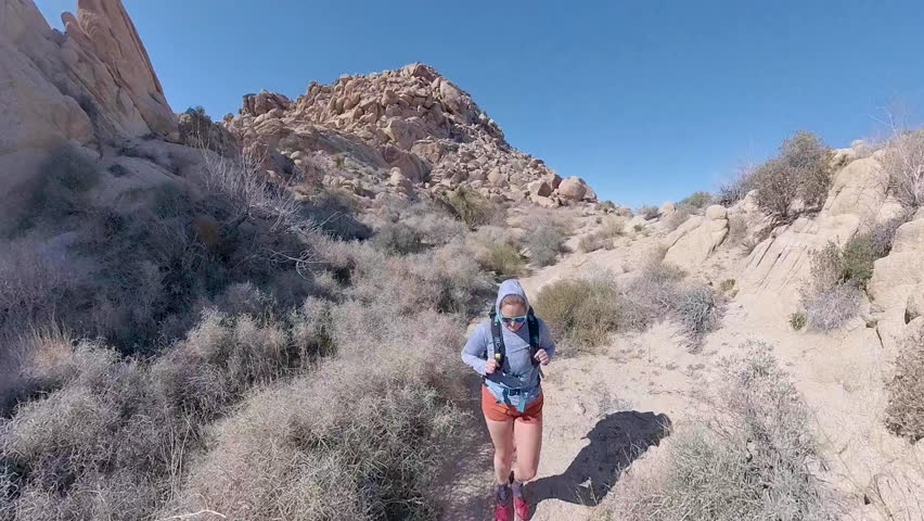 Woman Walks through Canyon of Boulders in Joshua Tree
