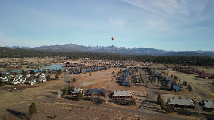 Aerial of hot air balloon over neighborhoods and lake in Pagosa Springs Colorado in winter