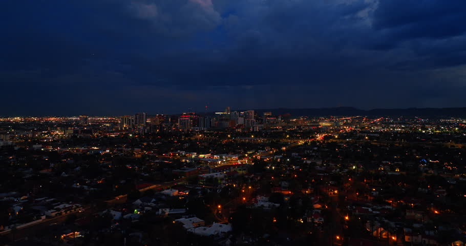 Dark heavy rainy clouds above the big lively city. Night view of Phoenix, Arizona, the USA from top.