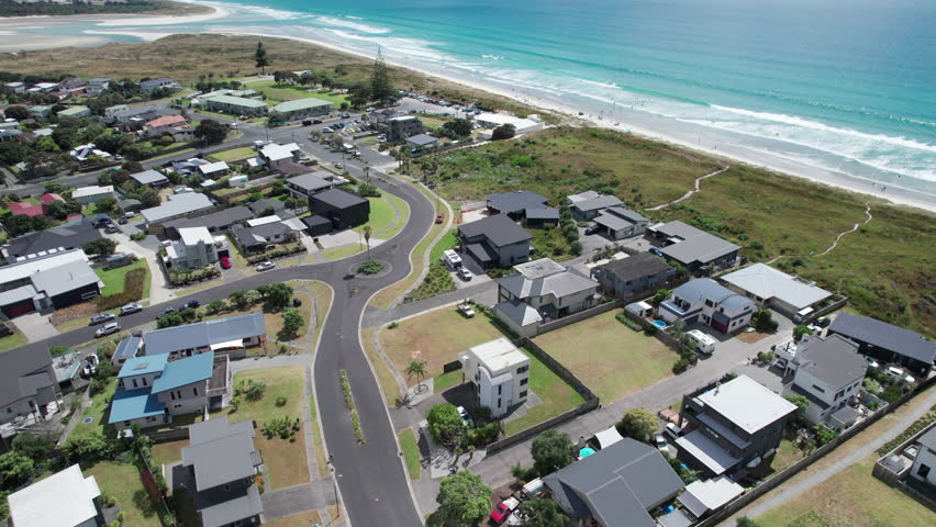 Beachfront suburb in New Zealand, Ruakaka, with clear blue water and golden sand.