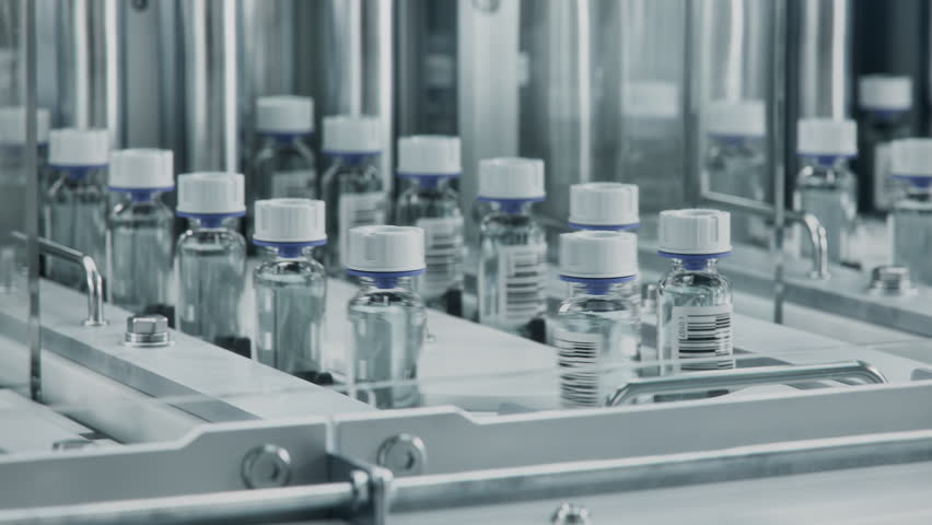 Close-up of Medical Glass Vials with White Caps on Conveyor Line at Modern Pharmaceutical Factory. Medicine Manufacturing Process. Medicinal Drug Production Plant. 