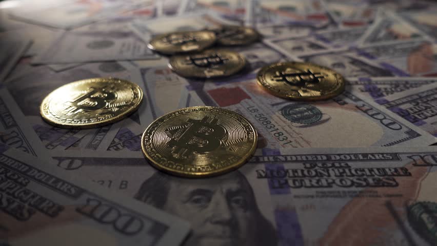 Close-Up of shiny bitcoin crypto currency coins on top of a 100 dollar bill. Rotating shot of Bitcoins digital cryptocurrency and dollar bill. Finance and investment concept