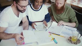 A diverse team is actively brainstorming and discussing various creative projects using documents and a tablet - Powered by Shutterstock - Get 15% off with code: PIKWIZARD15