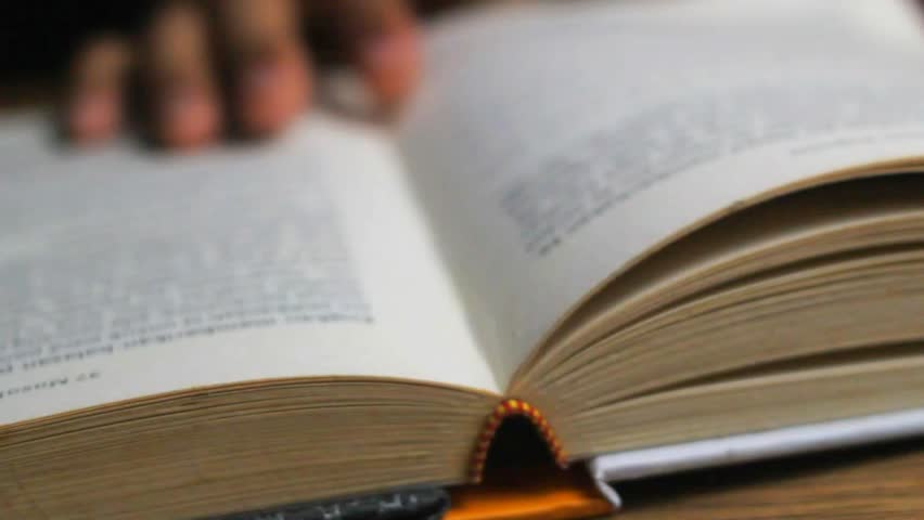 close up of unknown man's hand turning the pages of a book