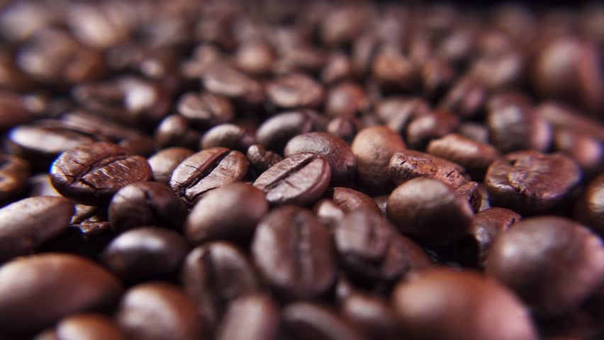 Slow motion of coffee beans falling into Pile of coffee beans. Freshly roasted strong aromatic coffee beans in a large pile.
