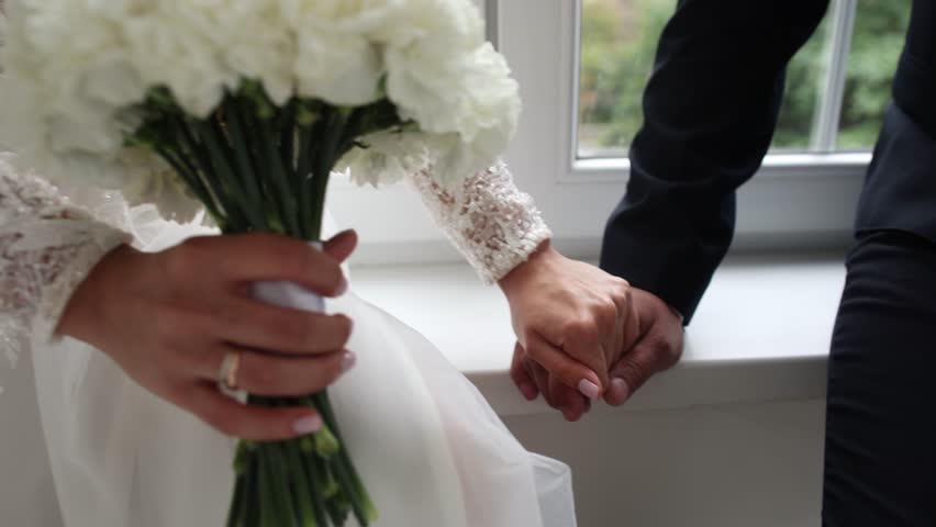 bride's hand with a wedding ring on a wedding dress
