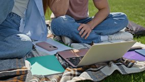 Man hand showing laptop screen to woman at outdoors study session closeup. Two young students collaborating on project at green campus lawn. Smiling couple using computer relaxing at picnic in park. - Powered by Shutterstock - Get 15% off with code: PIKWIZARD15