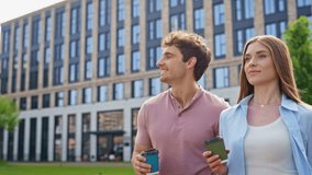 Smiling man woman walking together with coffee outside near modern office building closeup. Two professionals enjoying morning conversation in urban setting. Happy friends strolling sunny street. - Powered by Shutterstock - Get 15% off with code: PIKWIZARD15