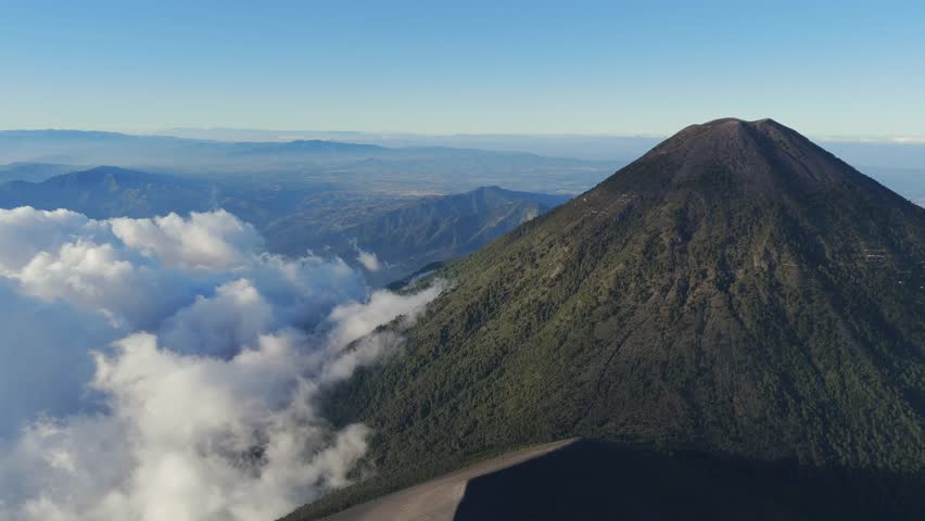 Incredible landscape of the Acatenango volcano with thick clouds on its slopes and more mountains in the background in Guatemala