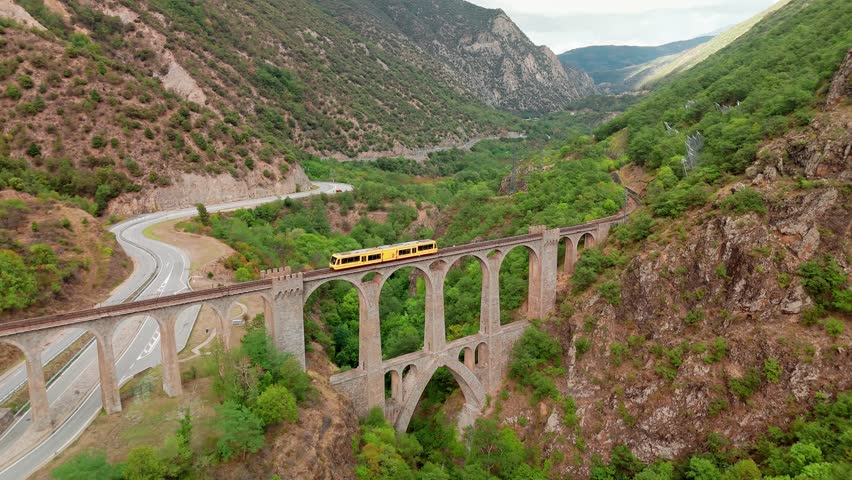 Aerial view of the little yellow train crossing the beautiful viaduct bridge in Mont-Louis, Pyrenees-Orientales, France. Le Petit Train is popular tourist attraction in French Pyrenees