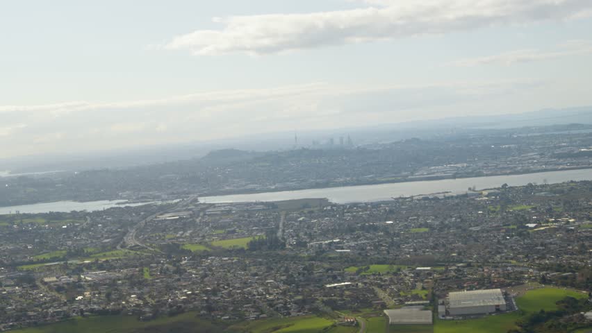 Aerial wide shot of Auckland Cityscape with river and skyline in distance. sunny day with clouds in New Zealand. View from airplane during take-off