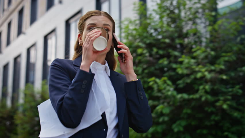 Overwhelmed businesswoman talking smartphone hurrying on work with coffee cup closeup. Busy woman boss walking city street calling cellphone. Young lady going to office calling mobile phone at morning