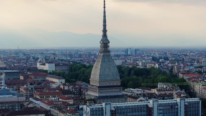 A breathtaking aerial shot of the Mole Antonelliana rising against the dramatic snow-capped Alps on the horizon.