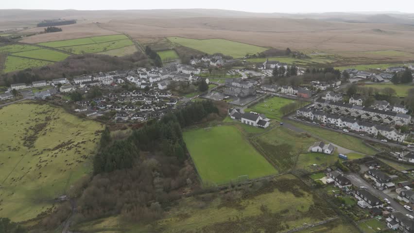Elevated aerial of Princetown’s compact homes, meandering roads, and surrounding green fields, reflecting a tranquil rural lifestyle beneath open skies
