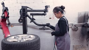 Skilled female mechanic working on a tire mounting machine in a professional car repair shop - Powered by Shutterstock - Get 15% off with code: PIKWIZARD15