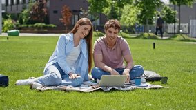 Friends talking at virtual conference sitting together on park grass sunny day. Positive man woman video calling by laptop relaxing on lawn. Smiling young couple communicating online at family leisure - Powered by Shutterstock - Get 15% off with code: PIKWIZARD15