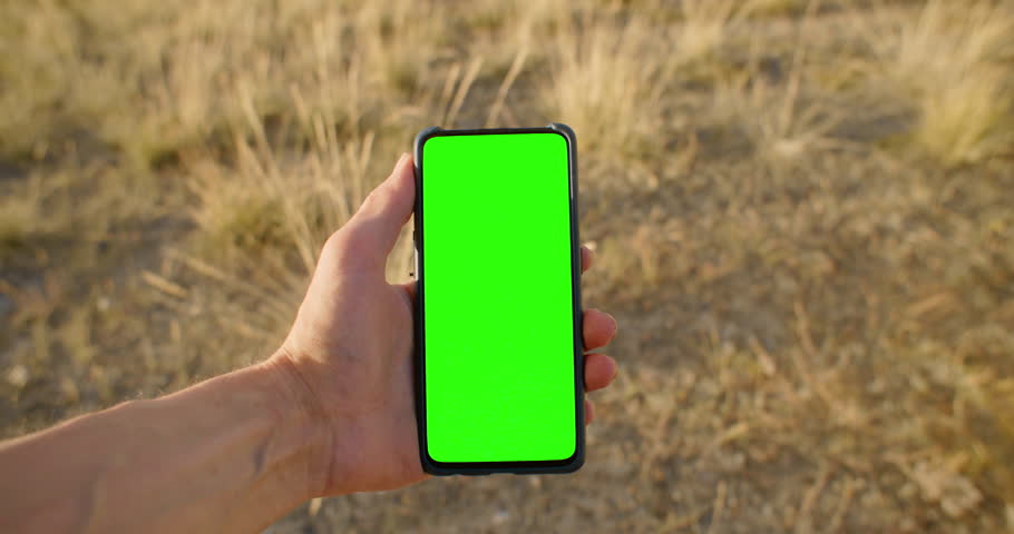 POV Person wearing holding mobile phone and not touching touch screen. Use green screen for copy space closeup. Chroma key mock-up on smartphone in hand.