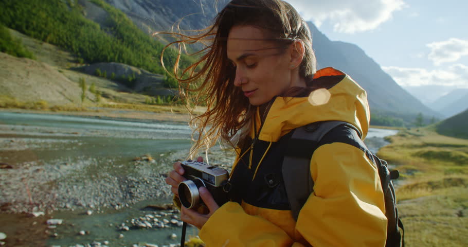 Female photographer taking pictures with vintage camera of a stunning river landscape under vibrant skies