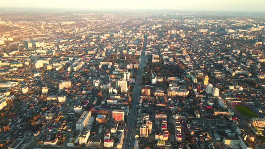 Aerial drone view of Chisinau downtown at sunset. Multiple buildings, trees, parks, road with mooving cars. Moldova