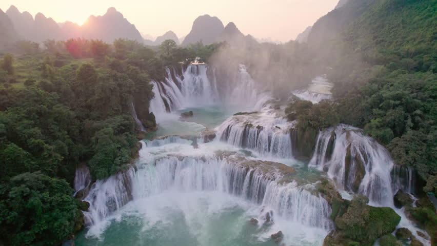 Aerial view of majestic Ban Gioc Waterfall, Detian Falls flowing amidst tropical forest during the sunset at Cao Bang, Vietnam