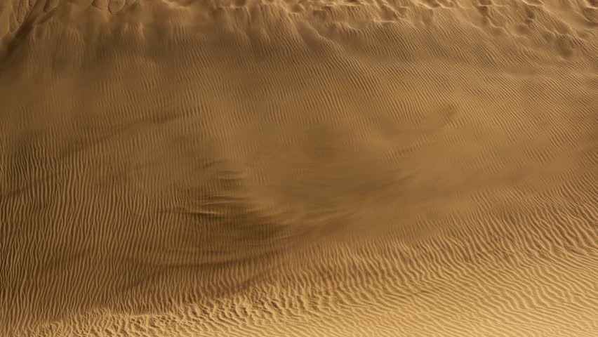 Sand waving in the wind in dunes in desert. Sandstorm in the deset. Wind blows sand off the dune and carries it away