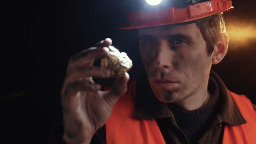 Gold Prospector Examining a Gold Nugget