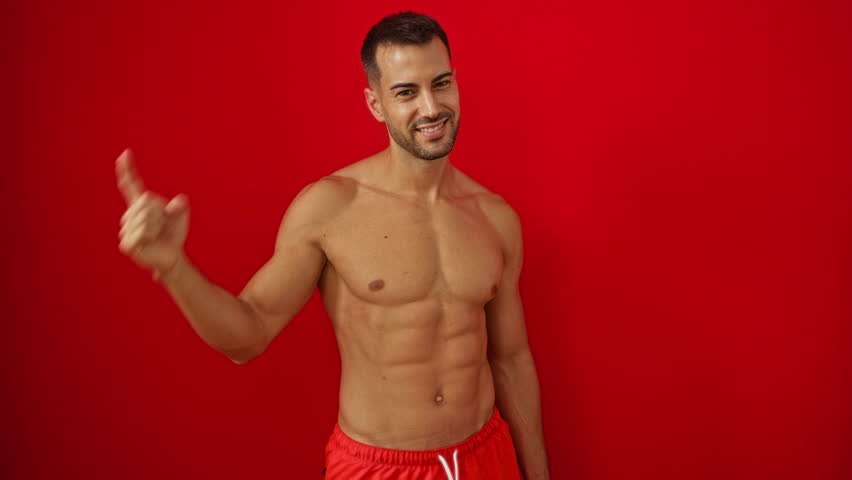 Young hispanic man shirtless in swimsuit smiling and pointing to head with finger, signaling great idea or good memory, isolated over red background