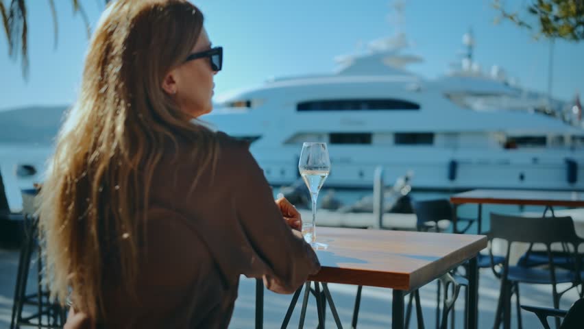 Portrait of business woman relaxing at a waterfront cafe with a luxury yacht view