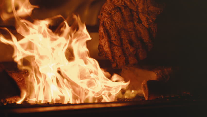 Flipping tomahawk steak in extreme slow motion on outdoor grill, flames and huge cut of beef in 4k 800fps